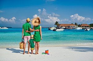 海滩上的家人穿着绿色衣服的轻夫妇和小孩