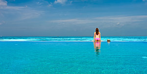 女人马尔代夫的无限游泳池里放松