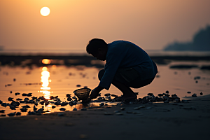 海边赶海夕阳捕捞摄影图